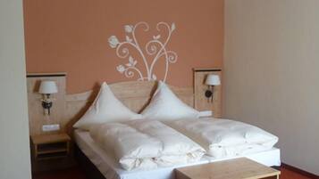 Una habitación de hotel con cama, mesita de noche y lámpara de pared.