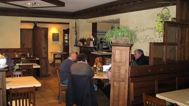 A restaurant interior with wooden furniture, a central table with a plant, and a wall with a sign. - Hotel-Gasthof-Fellner (Furth im Wald)