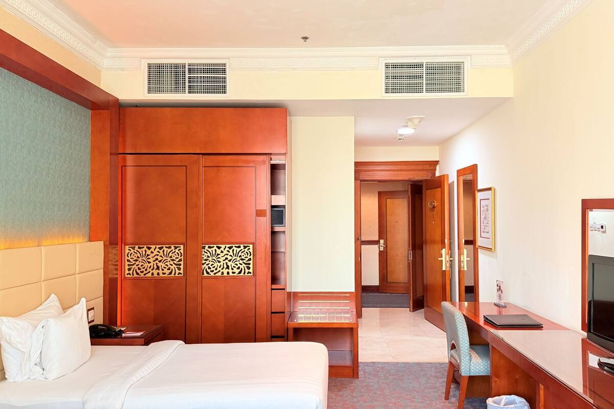 Une chambre d’hôtel comprenant un lit, un bureau avec une télévision, une chaise et une armoire.