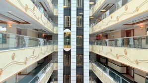 Een atrium met meerdere niveaus, glazen balustrades en decoratieve wandpanelen.