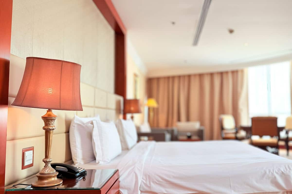 Une chambre d’hôtel comprenant un lit, une lampe de chevet, un téléphone, une télévision et un bureau avec une chaise.