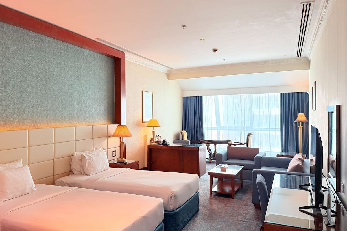 Une chambre d’hôtel avec deux lits, un bureau, un canapé et une télévision.