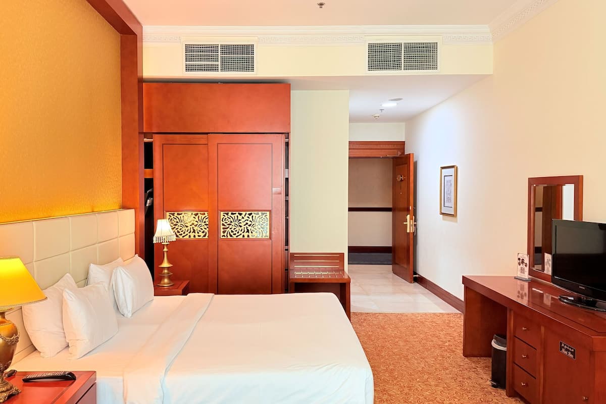 Une chambre d’hôtel équipée d’un lit, d’une lampe de chevet, d’une télévision, d’un bureau et d’une armoire.