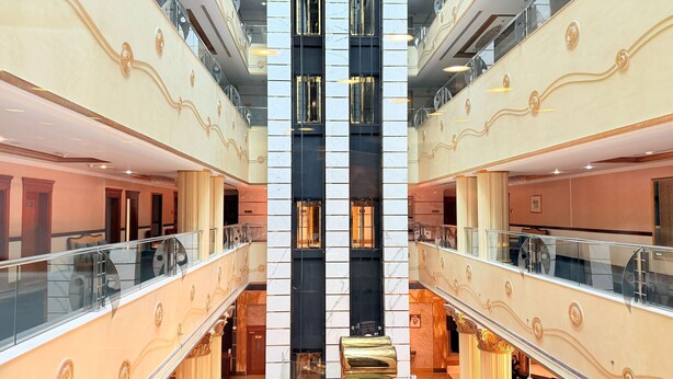 Een meerlaags interieur met glazen balustrades, een centrale kolom en een spiegelwand.
