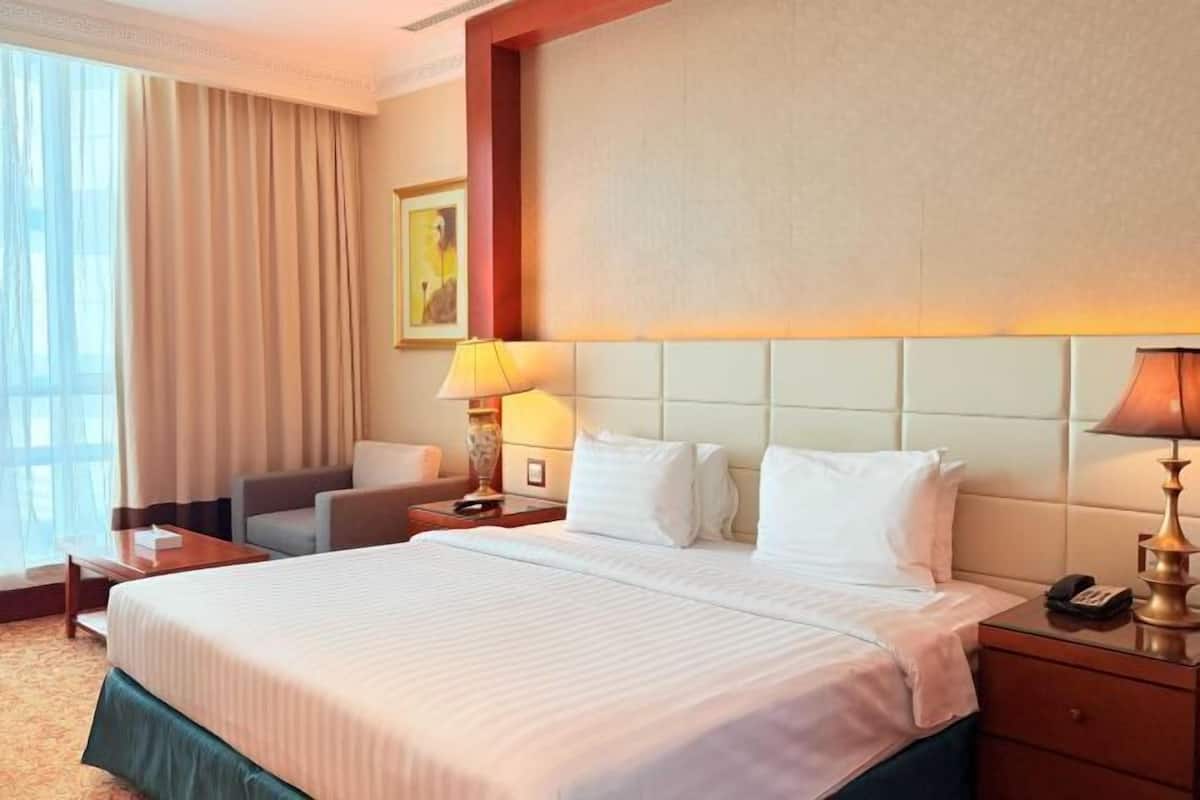 Une chambre d’hôtel avec un grand lit, un bureau, une chaise, une lampe et un tableau au mur.
