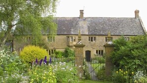 A stone house with a traditional design, featuring a well-maintained garden with various flowers and a lawn. - Lower Severalls Farmhouse (Crewkerne)