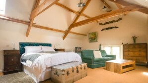 A bedroom with a bed, a green sofa, a wooden chest, and a small wooden table. - Lower Severalls Farmhouse (Crewkerne)