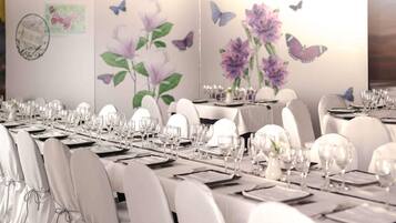 Een balzaal met lange tafels gedekt voor een formeel evenement, inclusief witte stoelen en servies.