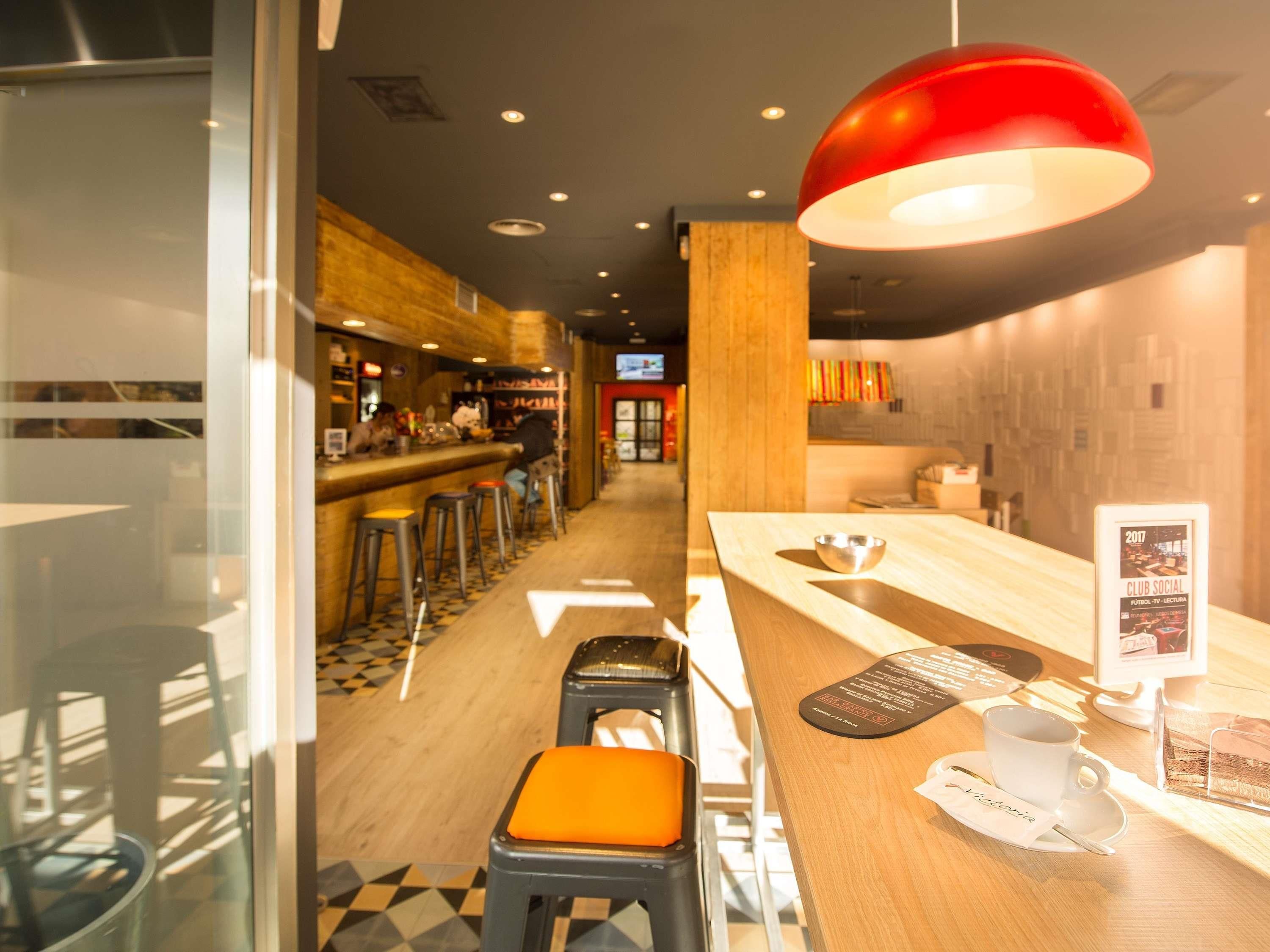 Zona de bar con taburetes, una barra y una lámpara colgante roja.