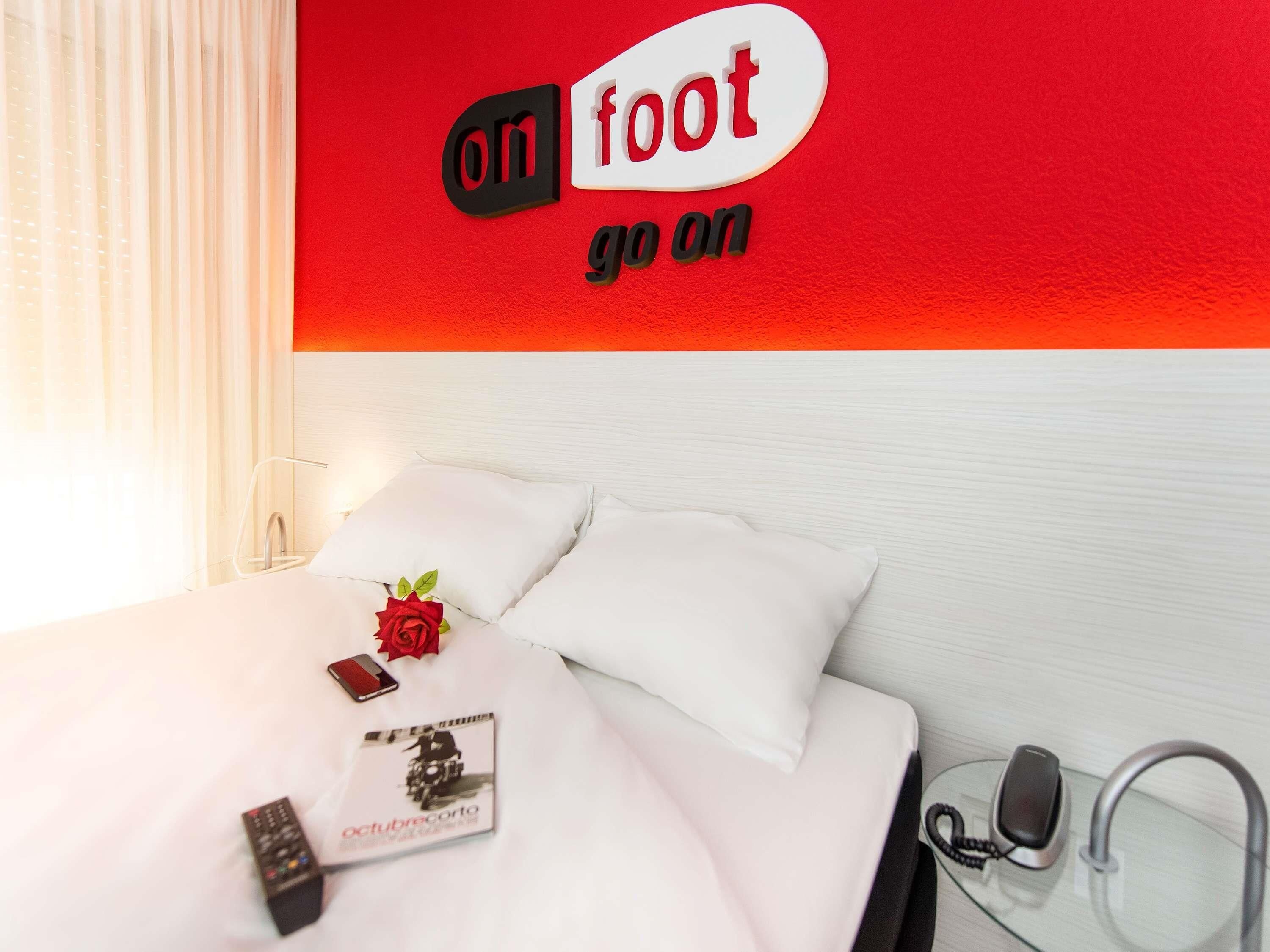 Une chambre d’hôtel avec un lit, une télécommande, un livre et un téléphone posés sur le lit.