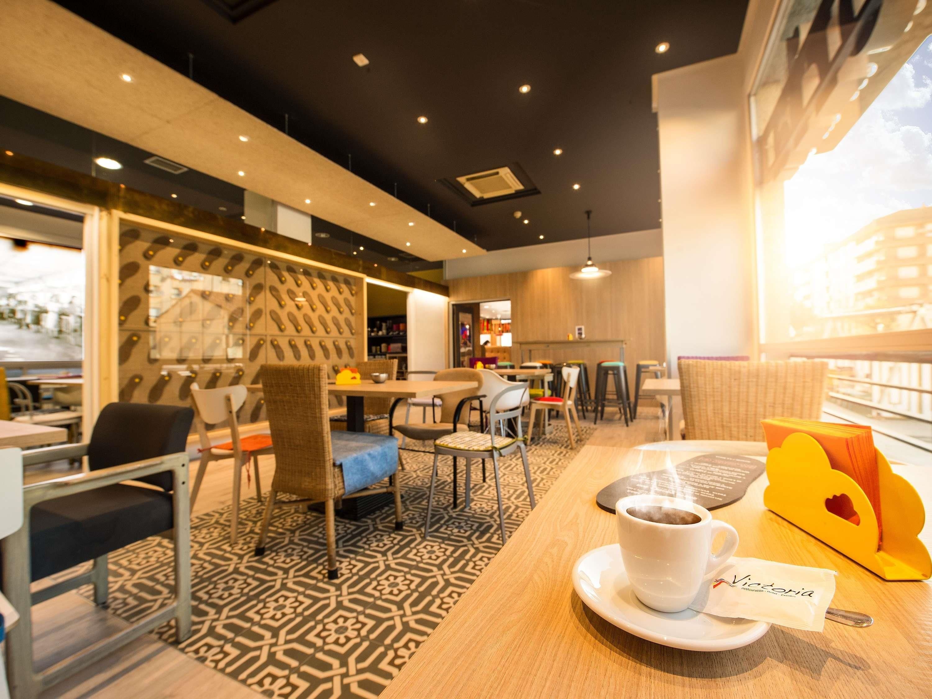 Ein modernes Café-Interieur mit einem gemusterten Boden, Holztischen und -stühlen.