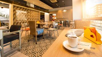 Ein modernes Café-Interieur mit einem gemusterten Boden, Holztischen und -stühlen.