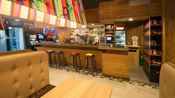 Una zona de bar con taburetes, una barra y un espacio de estar con una mesa y sillas.