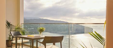 A balcony with a view of the sea and a distant mountain range.