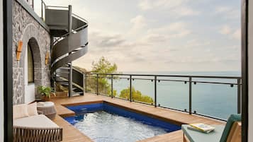 Una piscina moderna al aire libre con cubierta de madera, una escalera de caracol y vista al mar.