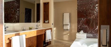 A modern bathroom with a marble vanity, a large mirror, a bathtub, and a towel rack.