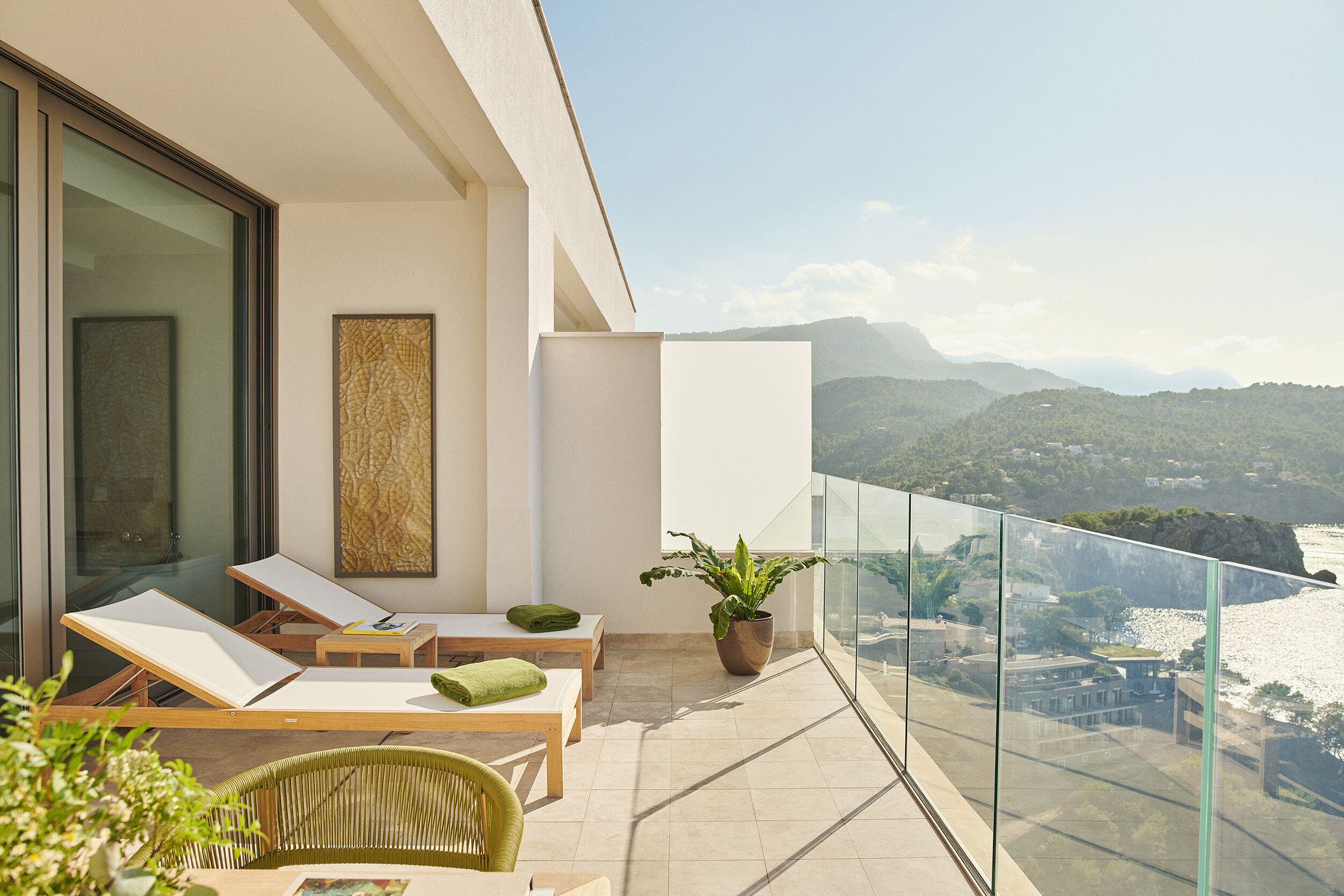 Un balcon avec deux fauteuils, une petite table et un pot de fleurs.