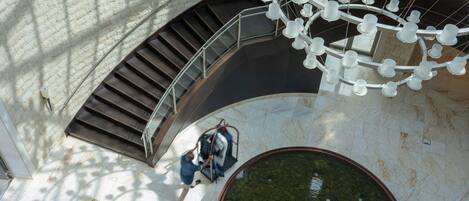 A circular water feature with a stone border, a staircase with metal railings, and a hanging light fixture with multiple bulbs.