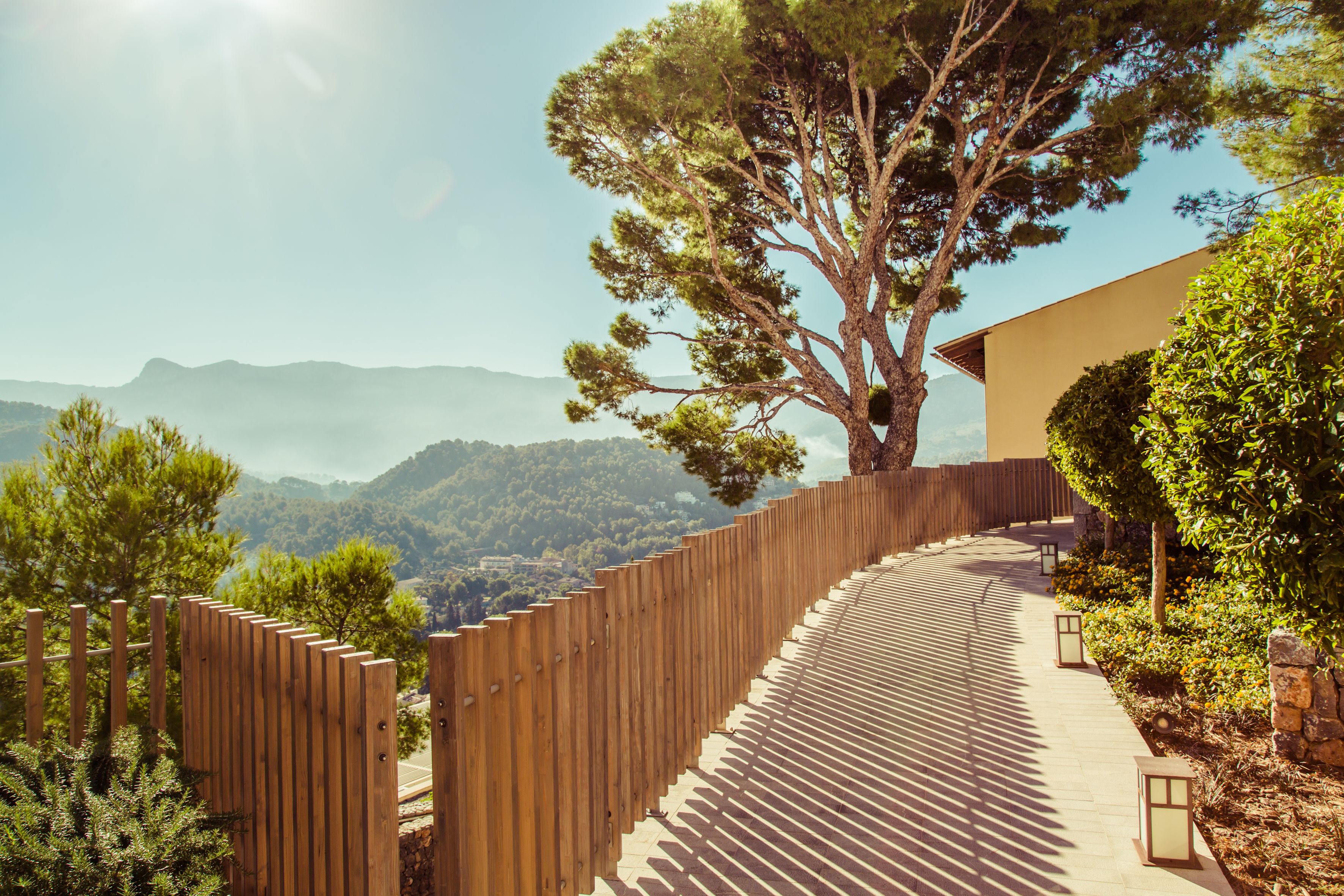 A wooden pathway leading to a building with a view of distant mountains.