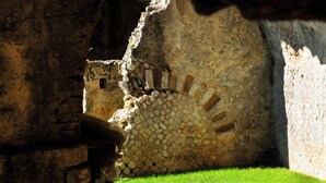 Un muro de piedra con diseño de ladrillo y un área verde al frente.