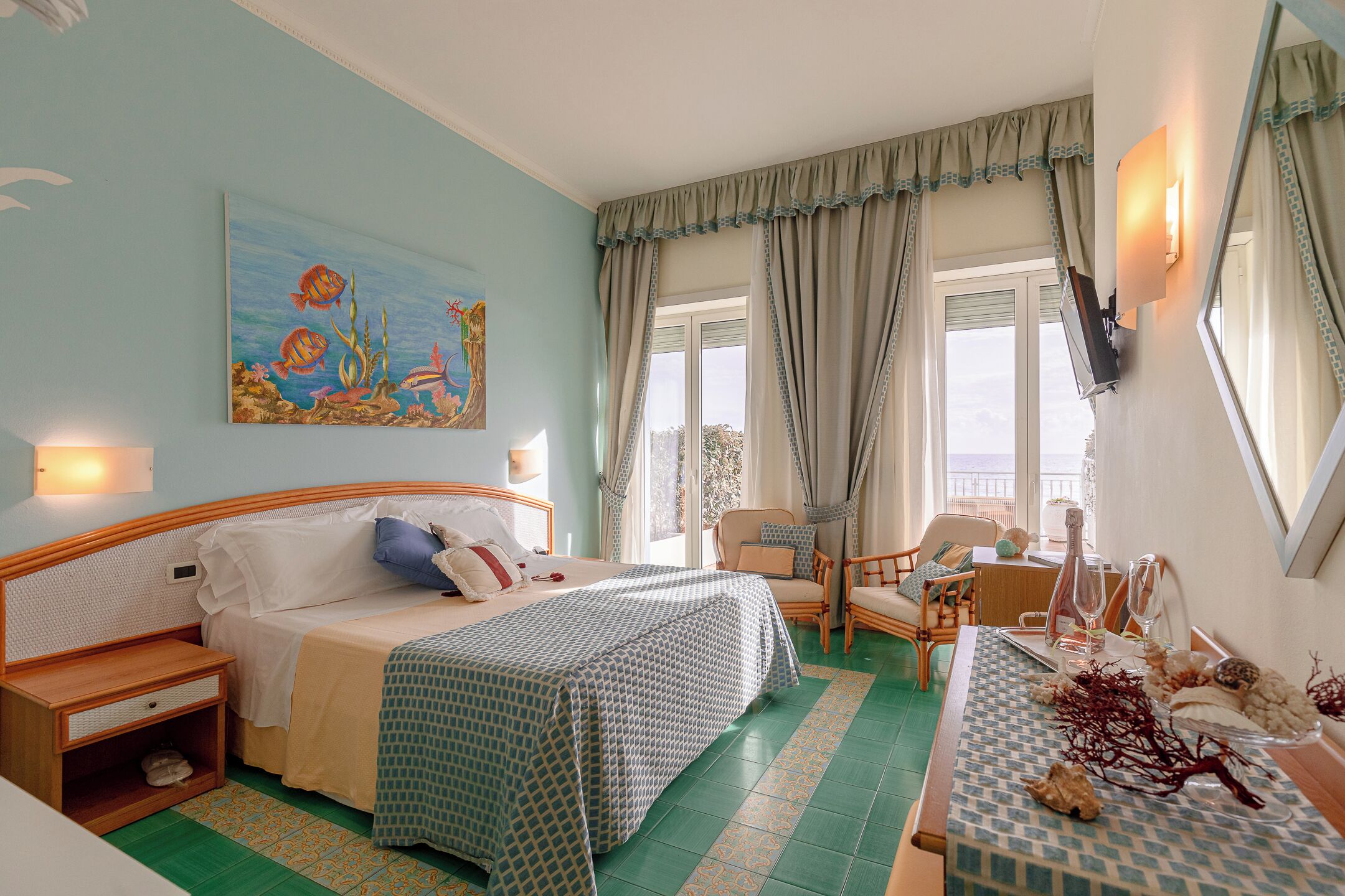 Una habitación de hotel con cama, mesita de noche y zona de comedor con mesa dispuesta para dos.