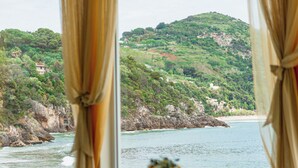 Un comedor con mesas dispuestas para una comida, con vistas a un paisaje costero con vegetación y acantilados rocosos.