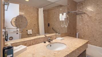 A bathroom with a marble sink, a mirror, a towel rack, a shower, and a hairdryer.