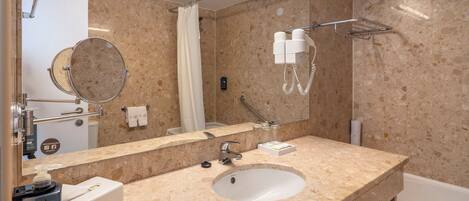 A bathroom with a marble sink, a mirror, a towel rack, a shower, and a hairdryer.
