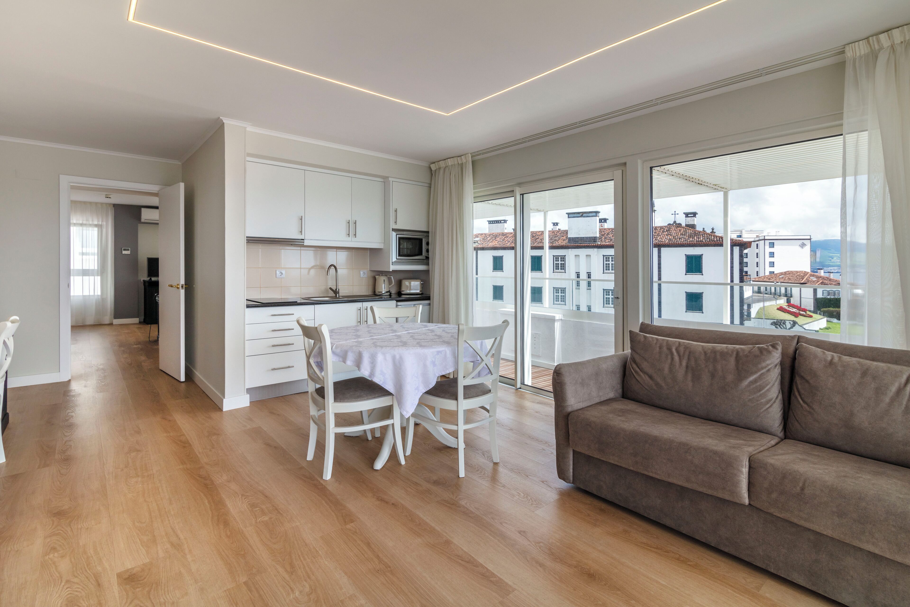 Eine moderne Wohnung mit Essbereich, Küchenzeile und einem großen Fenster mit Blick auf die Stadt.