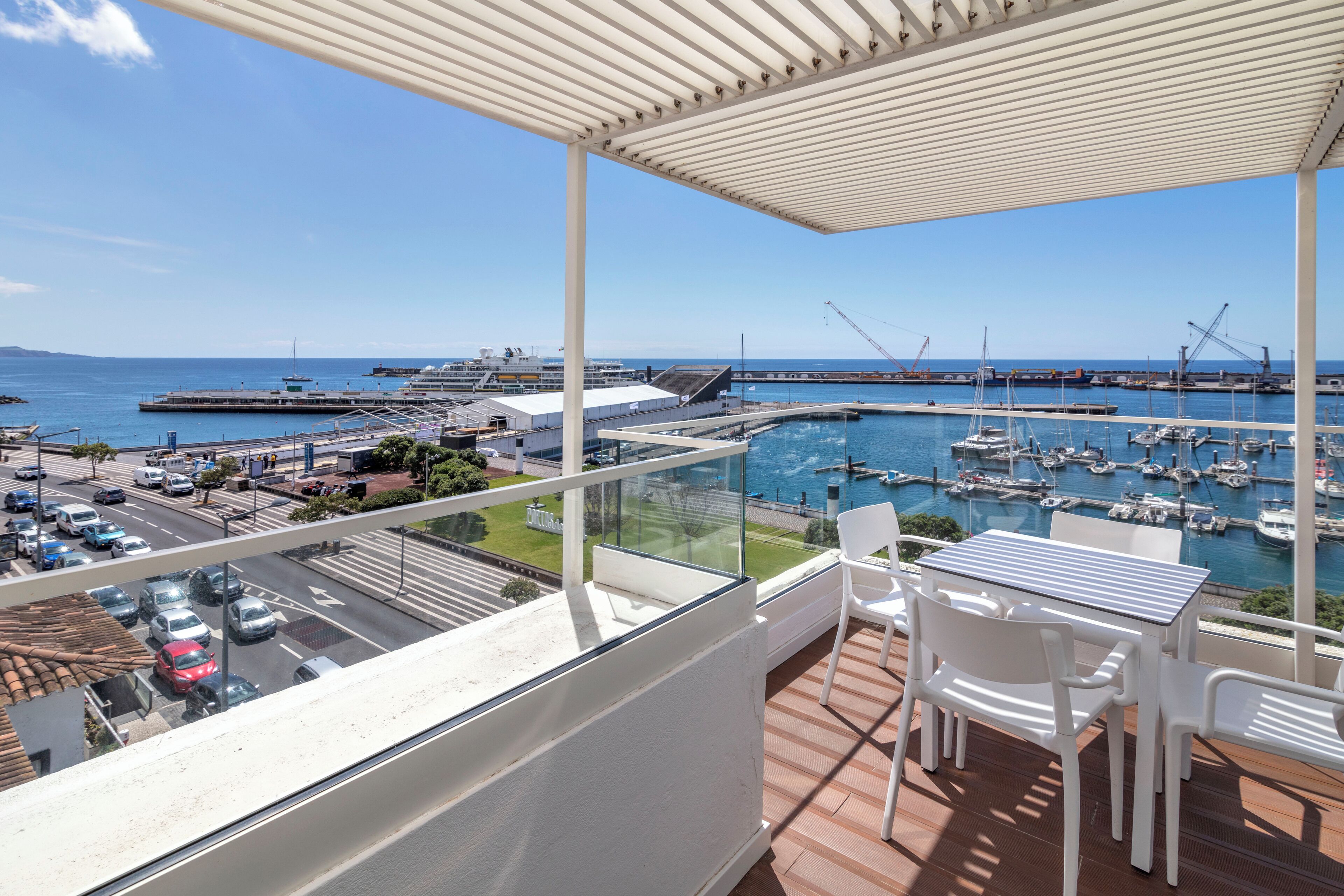 A balcony with a view of a marina, a table, and chairs.