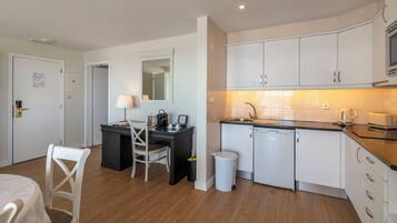 A modern kitchen with white cabinets, a black countertop, and a built-in dishwasher.