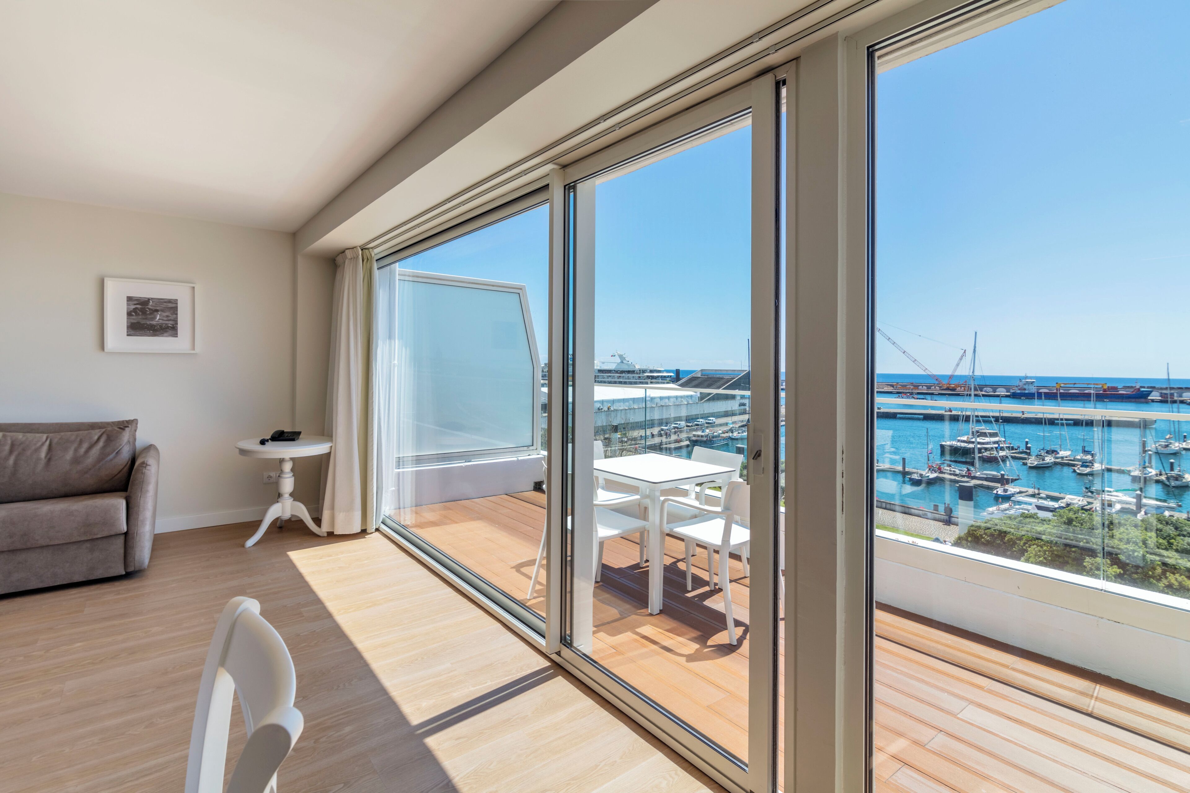A modern room with a large sliding glass door leading to a balcony with a view of a marina.