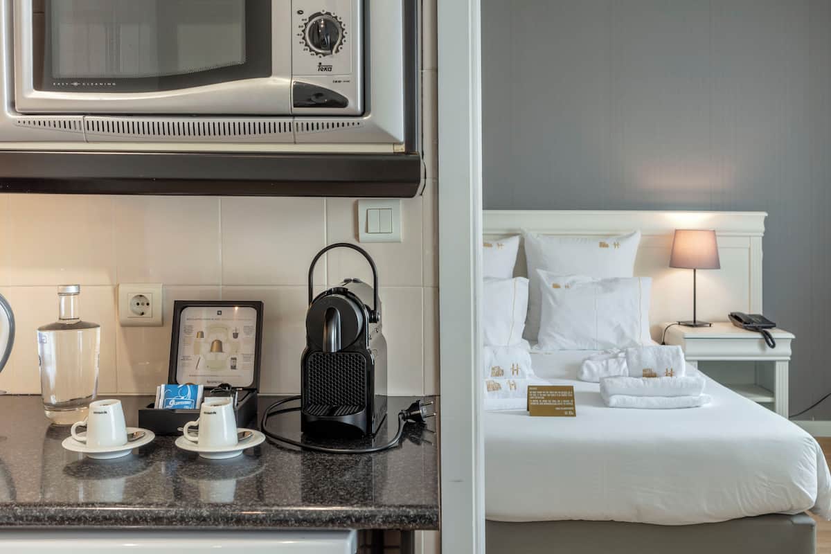 A hotel room with a bed, a bedside lamp, a nightstand, and a microwave above the counter.