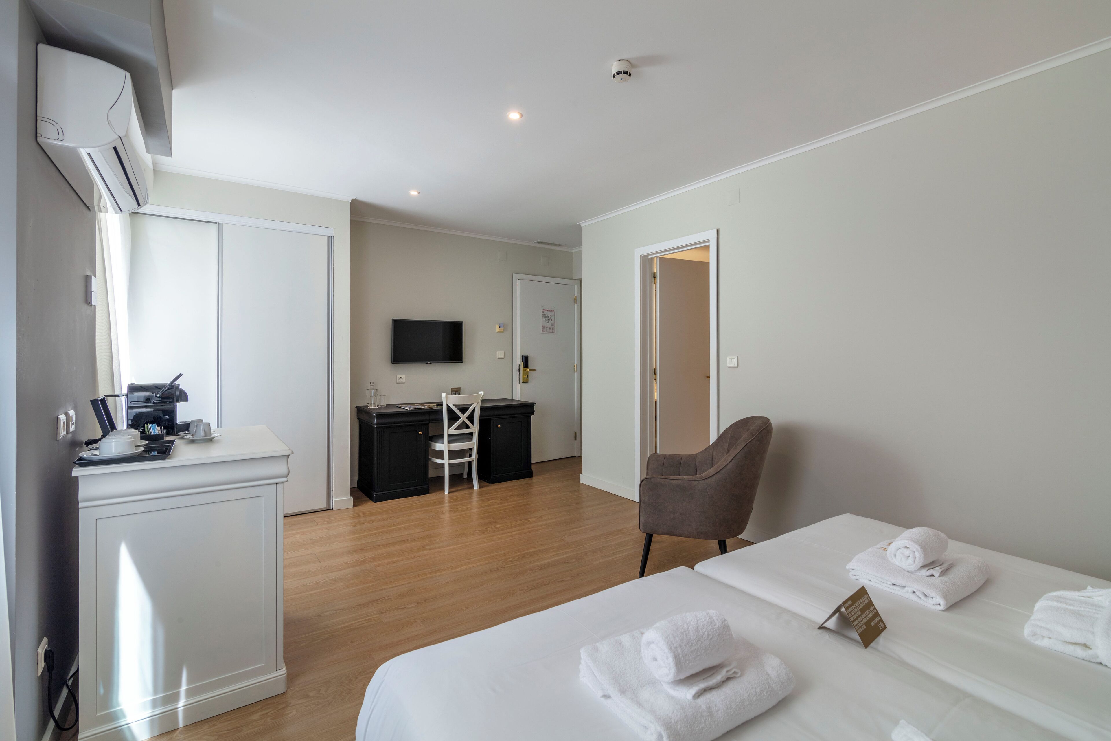 A hotel room with a bed, a desk, a chair, and a TV.