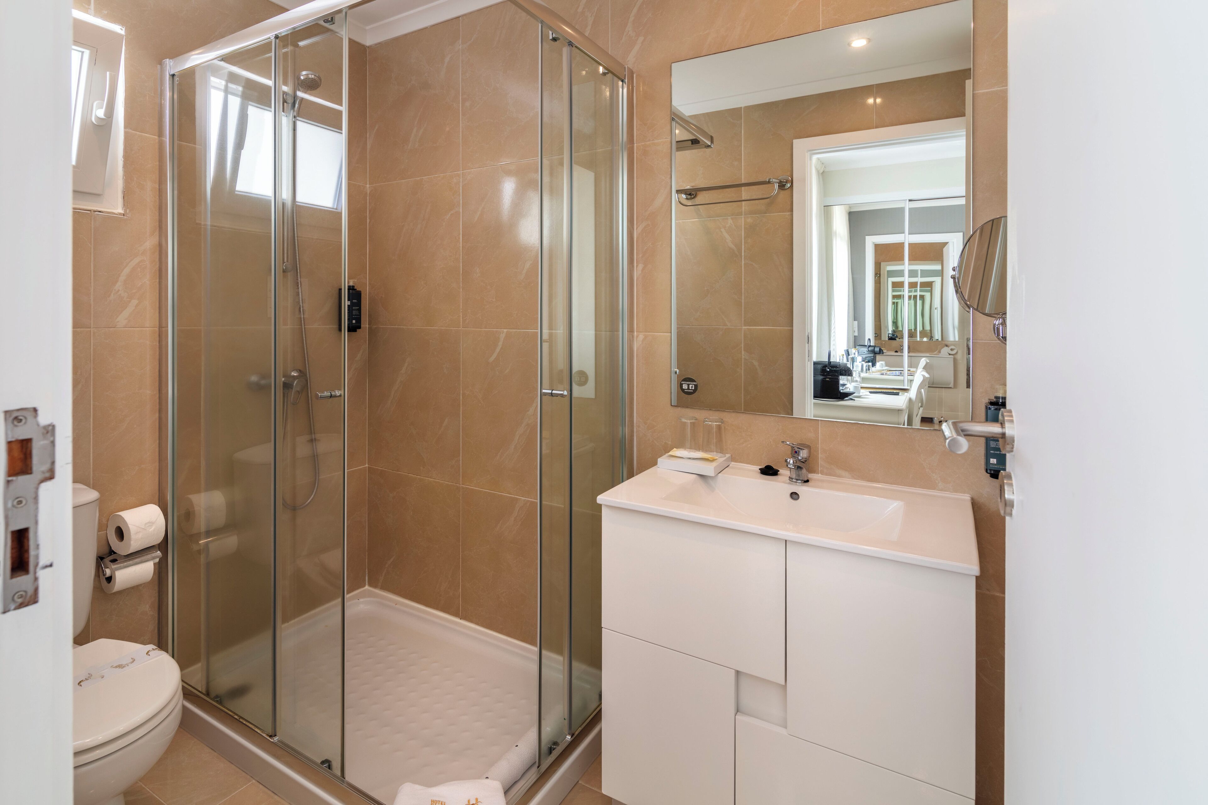 Une salle de bain moderne avec une douche à parois de verre, un lavabo blanc et un grand miroir.