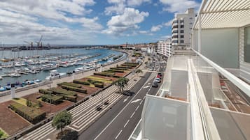 Un port esportiu amb vaixells, una carretera amb cotxes i edificis al fons.