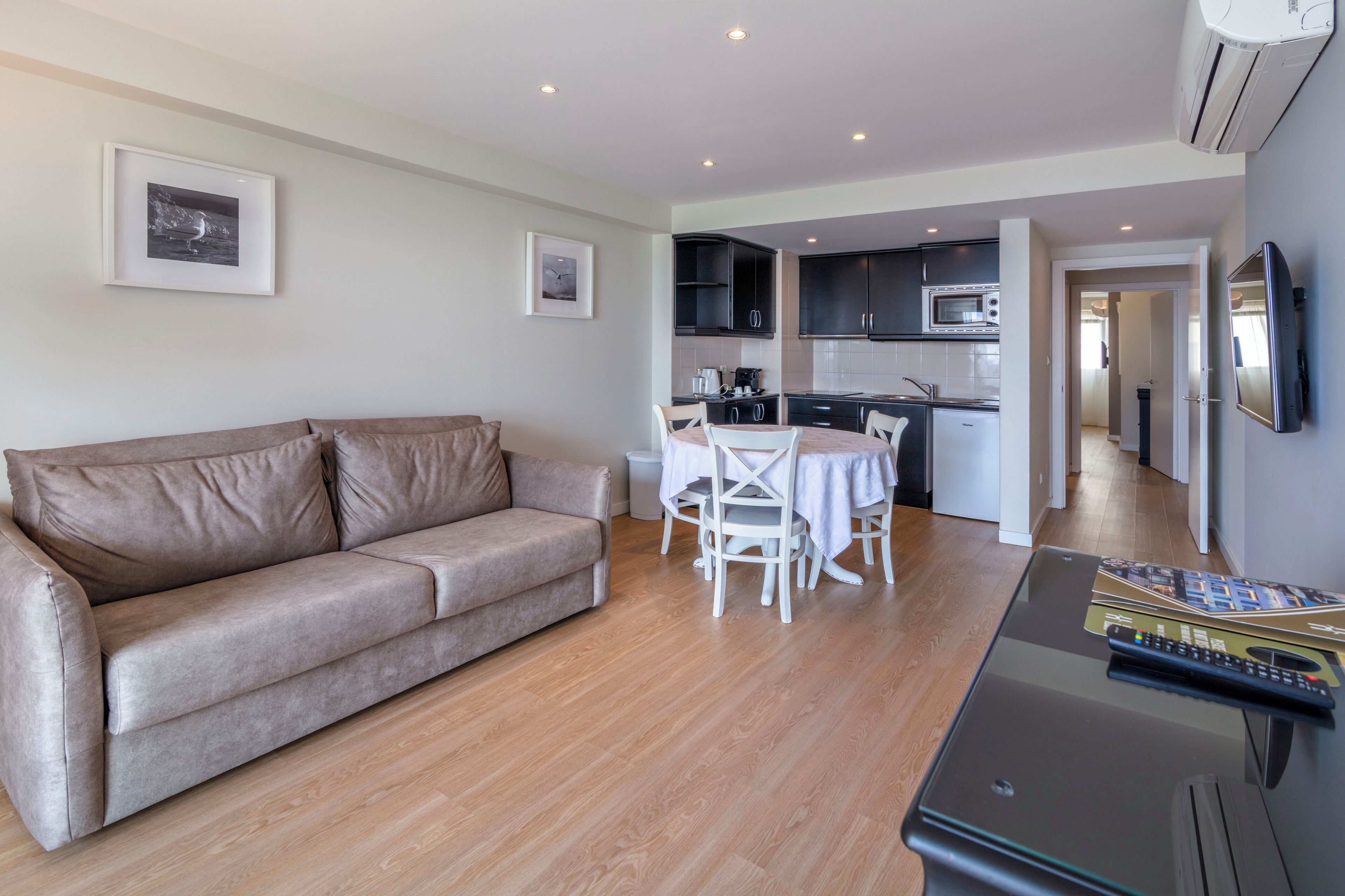 A living room with a sofa, dining table, chairs, and a TV.