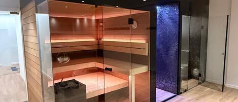 Una habitación moderna con separador de vidrio, suelo de madera y pared de mosaico azul.