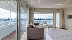 Una habitación de hotel moderna con un balcón amplio, un sofá, una mesa de comedor y una cama.
