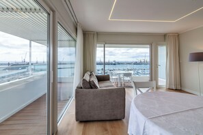 A modern hotel room with a large balcony, a sofa, a dining table, and a bed. - Hotel Gaivota Azores (Ponta Delgada)