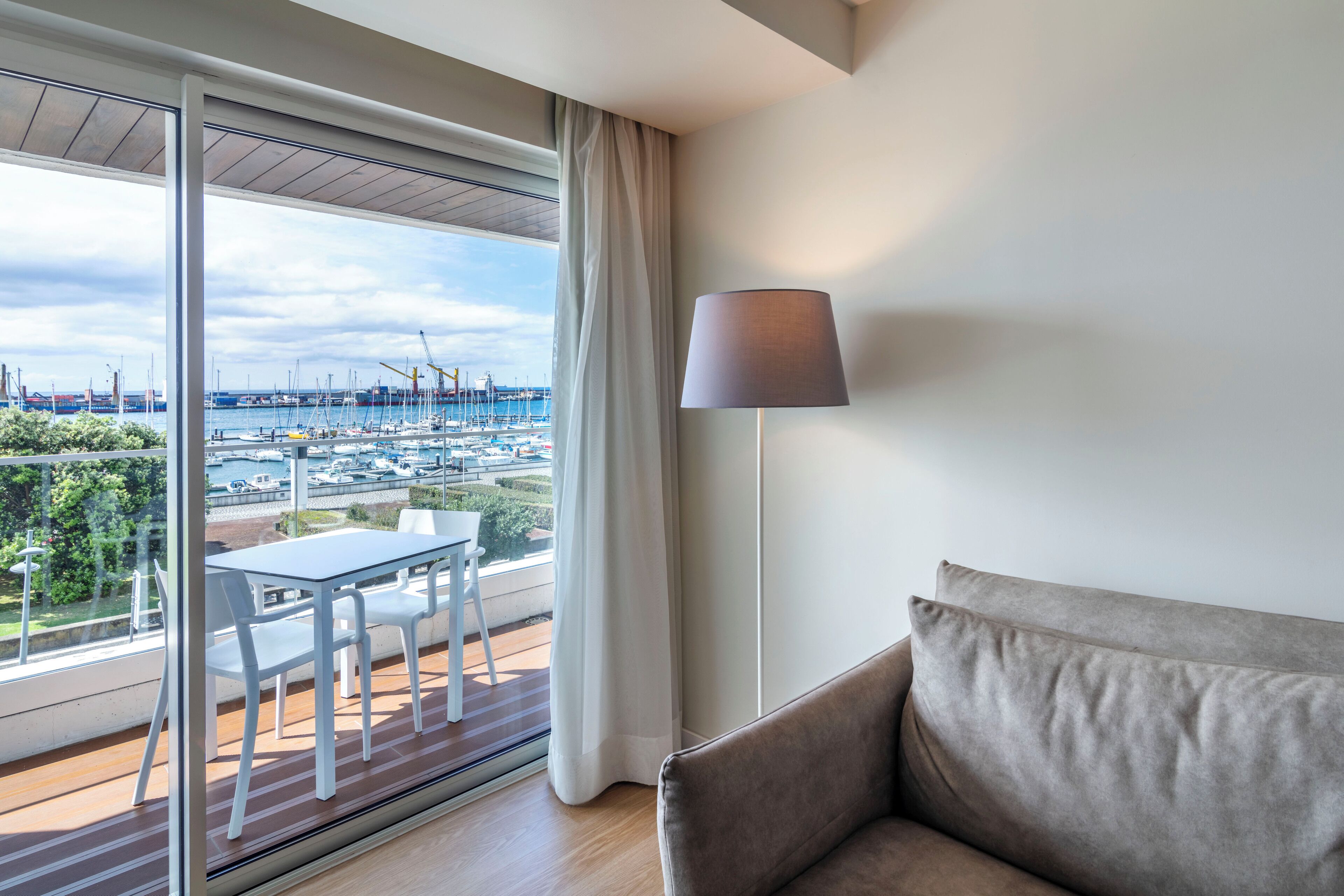A balcony with a table and chairs, a sofa, and a lamp.