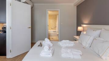 Une chambre d’hôtel avec un lit bien fait, une lampe de chevet et une vue sur la salle de bain.