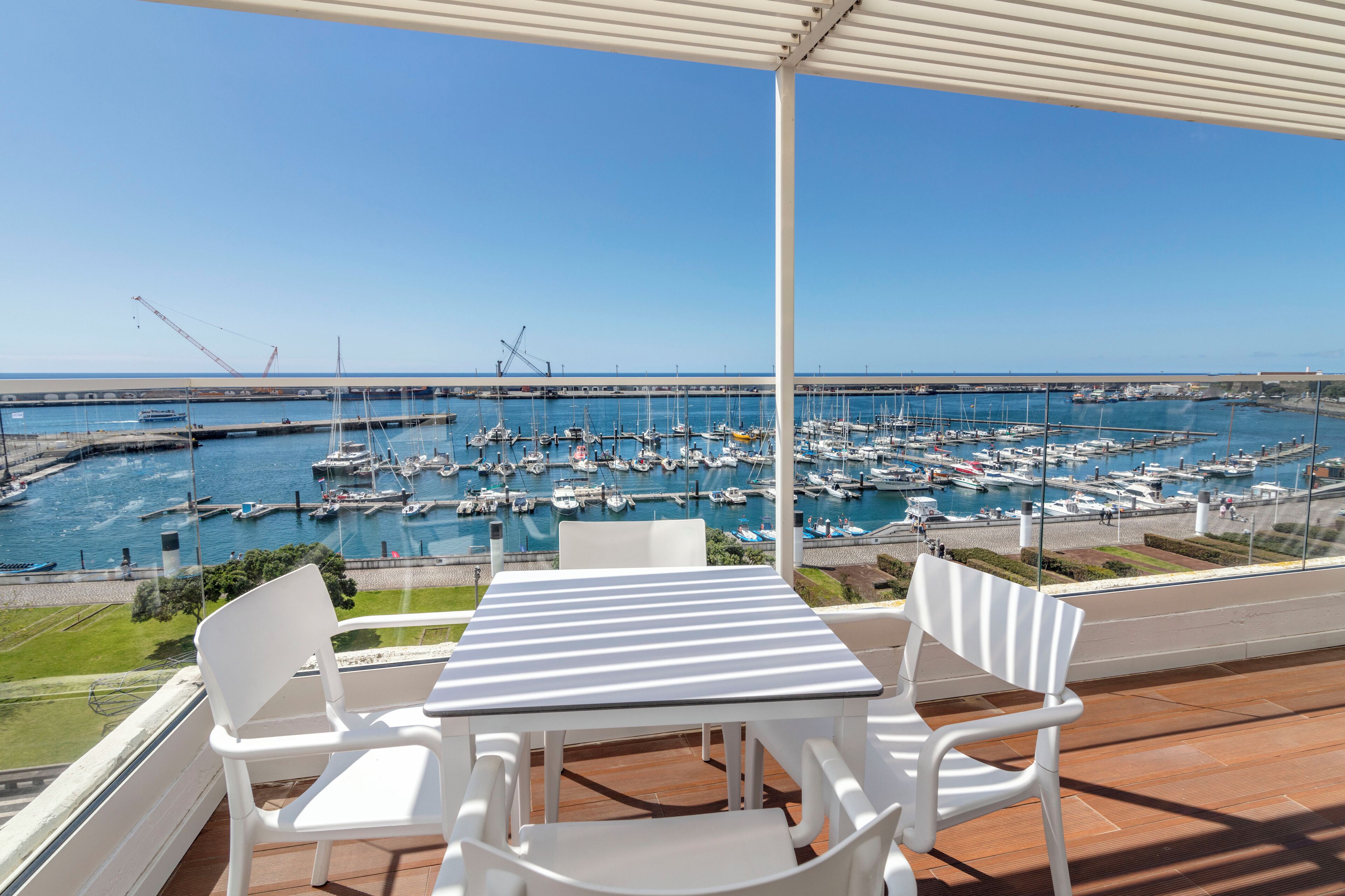 A terrace with a table and chairs overlooking a marina with numerous boats.