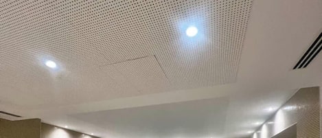 A swimming pool with steps leading up to it, recessed lighting, and a textured ceiling.