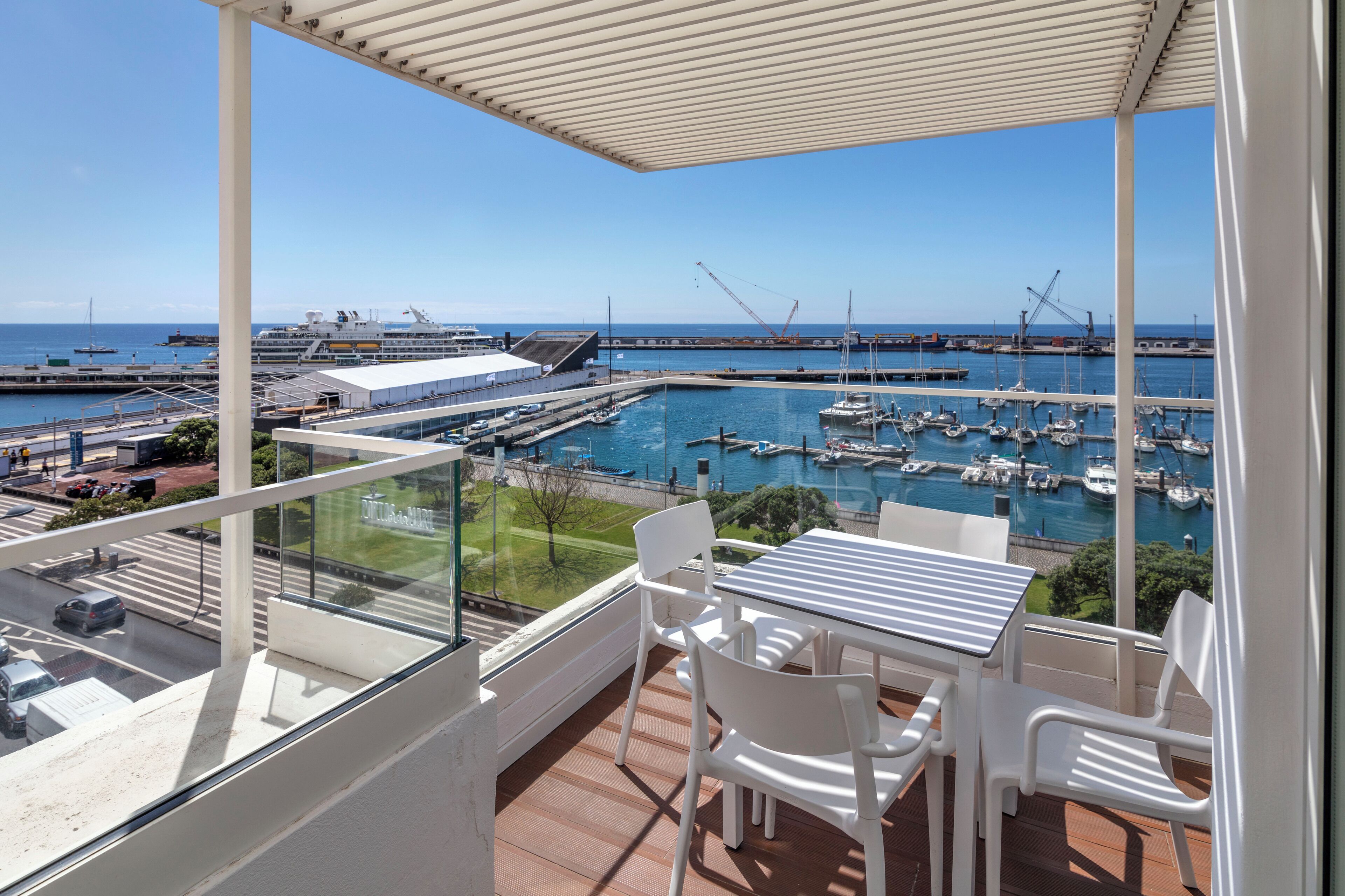 A balcony with a view of a marina, including boats and a cruise ship.