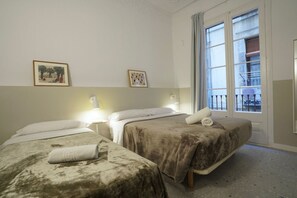 A hotel room with two beds, a window with a view, and two framed pictures on the wall. - Hostal Hera (Barcelona)
