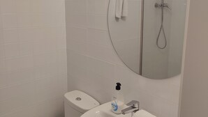 A bathroom with a toilet, sink, and a mirror above the sink. - Hostal Hera (Barcelona)