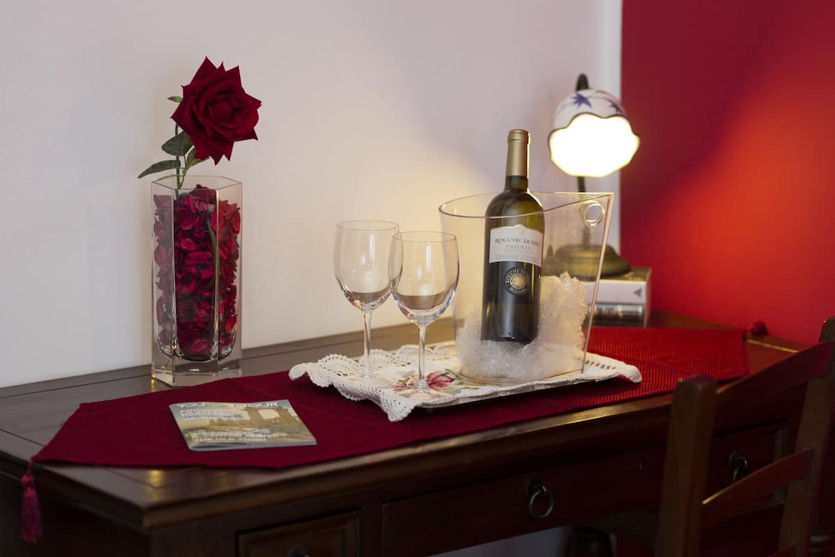 A table with a wine bottle, two glasses, and a vase with a single rose.