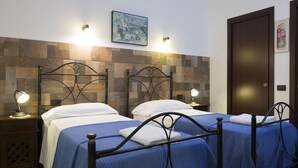 A hotel room with two beds, wooden headboards, and wall-mounted lights. - Le Cinque Novelle (Agrigento)