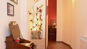 A hallway with wooden flooring, a piano, framed certificates on the wall, and a decorative plant. - Le Cinque Novelle (Agrigento)